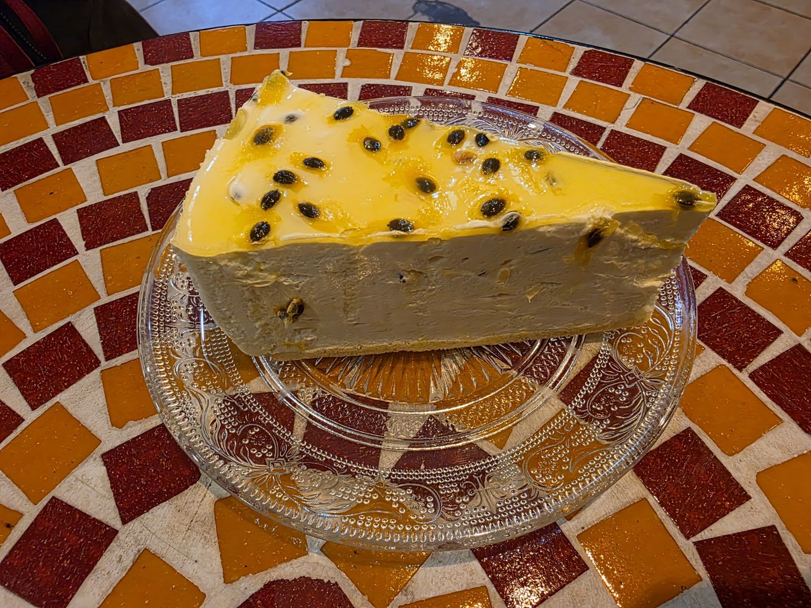 Cheesecake de maracuyá sobre mesa de mosaico