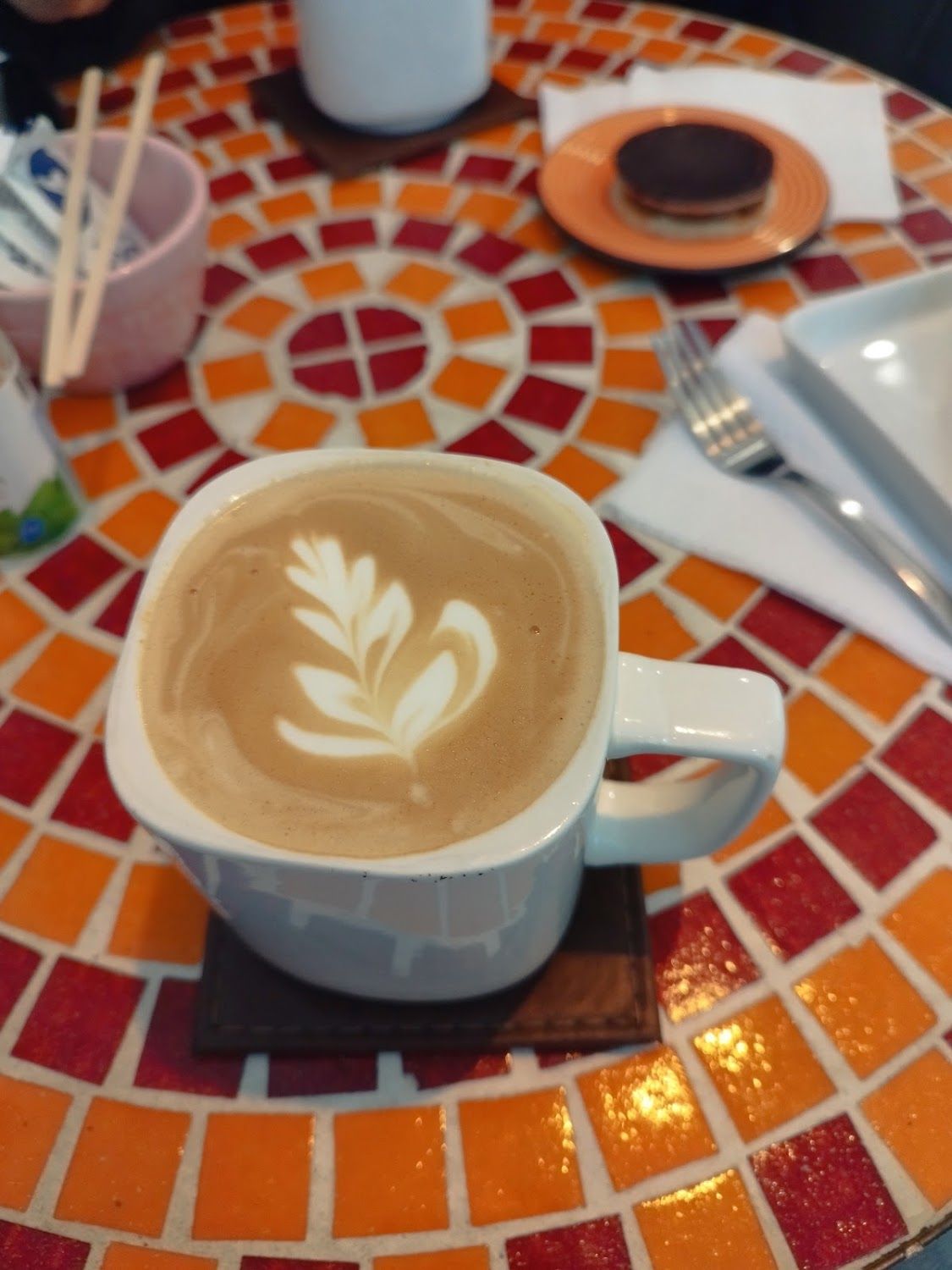 Capuchino con latte art servido sobre una mesa de mosaico en Cafetería Estado